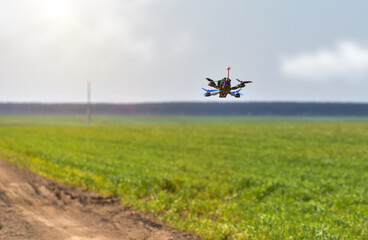 Racing drone flying over green field