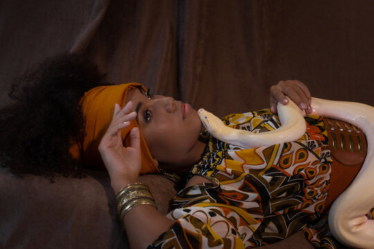 Art photo of a dark-skinned girl with a snake on her chest