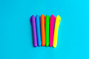 Magenta colored highlighters at cyan blue background with copy space