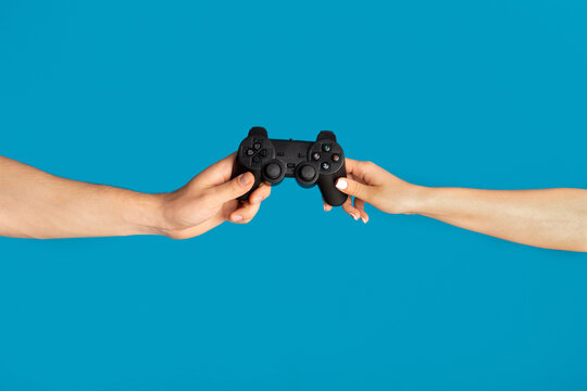 Young Man And Woman Pulling At Videogame Joystick On Blue Background, Close Up Of Hands