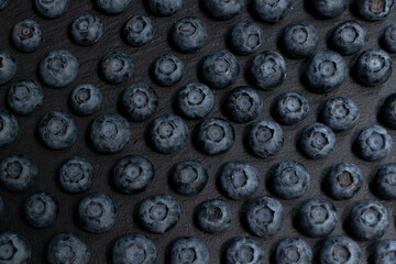 Symmetrical rows of blueberries on a black stone board. Stylish background. Berry.
