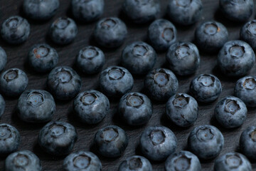 Symmetrical rows of blueberries on a black stone board. Stylish background. Berry.