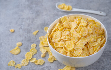 Corn flakes bowl sweeties with milk on gray cement background, close up, fresh and healthy breakfast design concept.