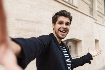 Happy young business man walking by street