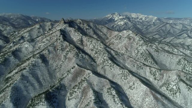 Epic mountainous natural landscape from great height. Winter rocky mountains network snow-capped peaks. Majestic reserve travel landmark Far East. Unique Asia scenery. Sunny blue sky. Drone sideways
