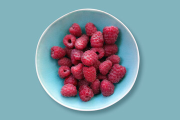 Raspberry close-up in a blue plate on a blue background. Selective focus