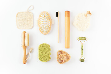 Reusable items for beauty treatment from organic biodegradable material, quartz face roller, anti cellulite massager, bamboo toothbrush, loofah sponge on white surface. Plastic free, ecology concept