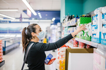 Young woman in face mask shopping in the supermarket during coronavirus outbreak