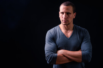 Muscular man with arms crossed against black background