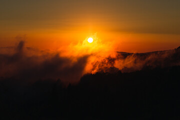 sunset between mountains and fog
