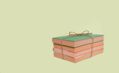 A stack of four books with colored covers tied with string laid out on a uniform background