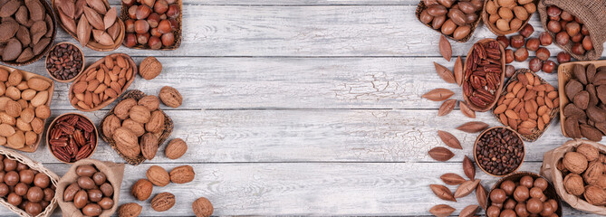 Panorama of various nuts on old wooden background.