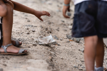 Selective focus of poor african american kid throwing dirty medical mask on ground near brother on urban street