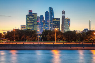 Towers of skyscrapers of Moscow city near the river with a reflection in the late summer evening in the center of the Russian capital.
