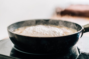 Hot boiling water in a black pan with floating steam. Boiling water for cooking spaghetti.