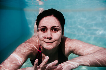 portrait of young woman diving underwater in a pool. summer and fun lifestyle