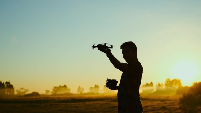 Man starts his drone aircraft from hand, taking off. Aerial shooting at sunrise