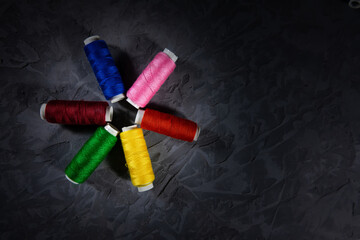 Multi-colored spools of thread folded with an asterisk