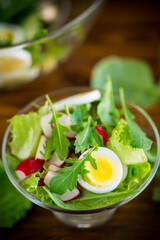 spring salad with arugula, boiled eggs, fresh radish, salad leaves in a glass bowl