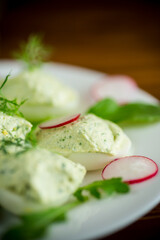 boiled stuffed eggs with green cheese filling with arugula leaves and radish
