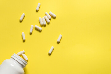 A jar with scattered tablets on a yellow background.