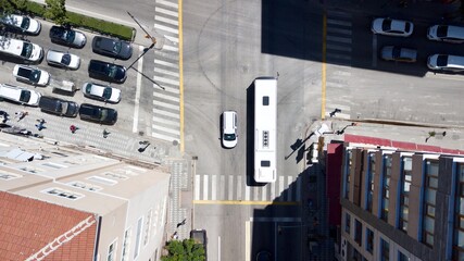 Aerial view of the crosswalk and road junction between buildings at the city center. Vehicles are...