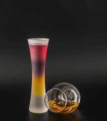 Colorful multi-layer drink and single malt whiskey in a specialist whiskey glass on a black background, party time