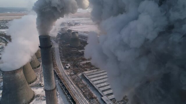 Epic flight through dark smoke of factory high many pipes. Dramatic abstract industrial plant emits pollutants into atmosphere worsens the ecology. Global warming. Mass scale epic production. Drone