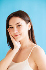 Lovely young woman with healthy skin against blue background