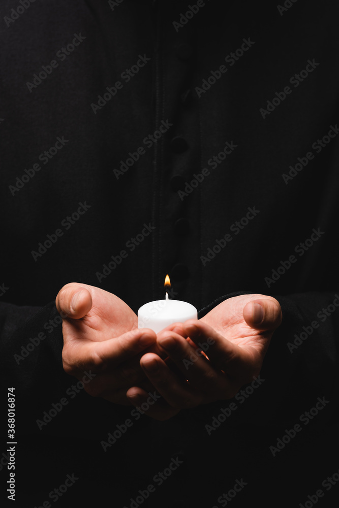 Wall mural cropped view of pastor holding burning candle isolated on black - Wall murals