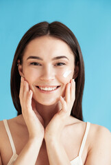 Lovely young woman with healthy skin against blue background