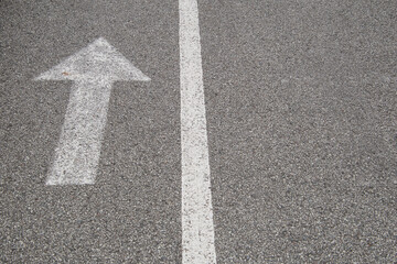 Arrow with a line, white paint on small grain asphalt.