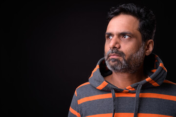 Portrait of mature bearded Indian man with curly hair wearing hoodie