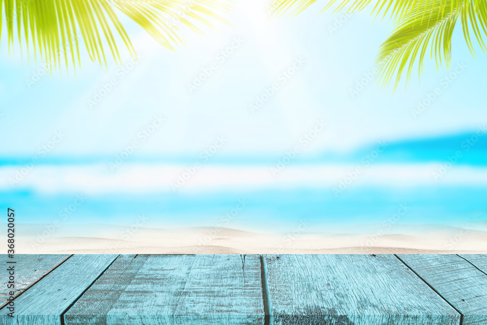 Poster blur tropical beach with bokeh sun light wave and palm tree on empty old wood table abstract backgro