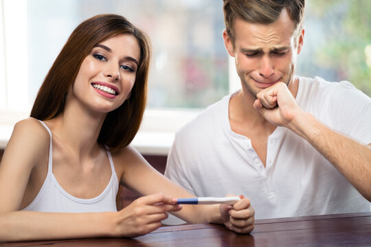 Funny image of young attractive couple, finding out results of a pregnancy test, at home. Good or bad news concept.