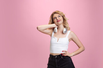 Dreamful, thoughtful. Caucasian young woman's portrait isolated on pink studio background. Beautiful blonde model. Concept of human emotions, facial expression, sales, ad, youth. Copyspace.