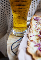 A glass of cold light beer. Very tasty and delicious pizza with tuna, red onion, cheese. Thin Italian pastry. Close-up, top view.