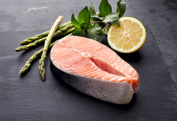 Salmon fish on the black background with asparagus, mint and lemon.  Steak on black background.