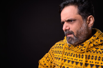 Portrait of mature bearded Indian man with curly hair wearing hoodie