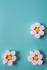 Chamomile with marshmallows and candy against a blue background. Edible flowers. Creative background with sweets