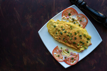 omelet with cooked ham cheese and tomato with green onion in white square plate