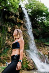 Young female nature explorer standing by the waterfall