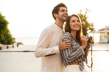 Fototapeta premium Image of young couple smiling while walking through city street