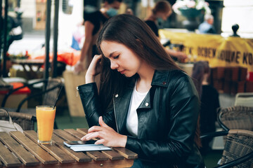 Young woman using her cell phone in outdoor restaurant