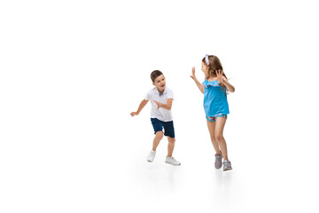 Happy kids, little and emotional caucasian boy and girl jumping and running isolated on white background. Look happy, cheerful, sincere. Copyspace for ad. Childhood, education, happiness concept.