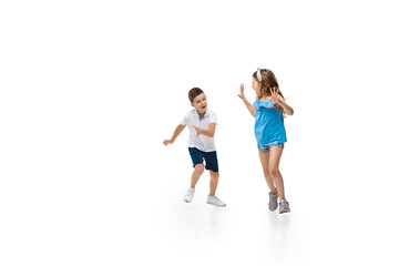Happy kids, little and emotional caucasian boy and girl jumping and running isolated on white...