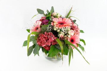 Ein feiner Festtagsstrauß mit Gerberas, Hydrangeas und Rosen in einer Kugelvase aus Glas