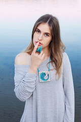 Beautiful young woman in jewelry on calm sea water background.