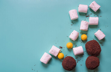 Three round chocolate cakes, white marshmallow and yellow candy. Beautiful blue background with sweets