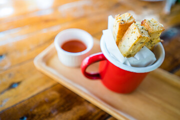 Garlic Bread In a red enamel container, on a Thai wooden table